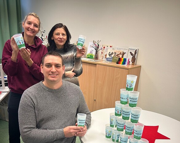Drei Personen der Schulleitung und des Schulvereins präsentieren Mehrwegbecher mit Logo vom Schulverein Witzlebenstraße